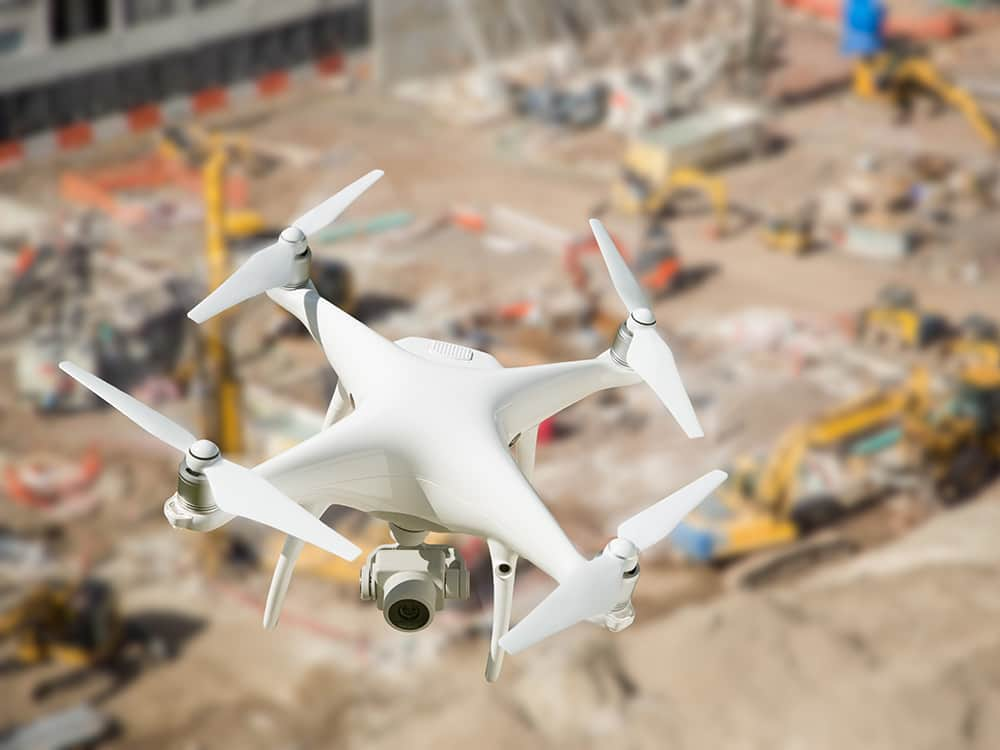 Unmanned Aircraft System (UAV) Quadcopter Drone In The Air Over Construction Site.