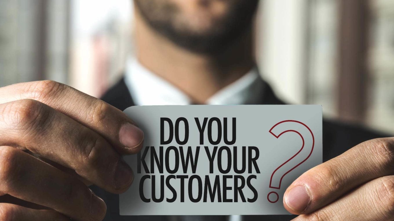 man holding card that says "do you know your customers