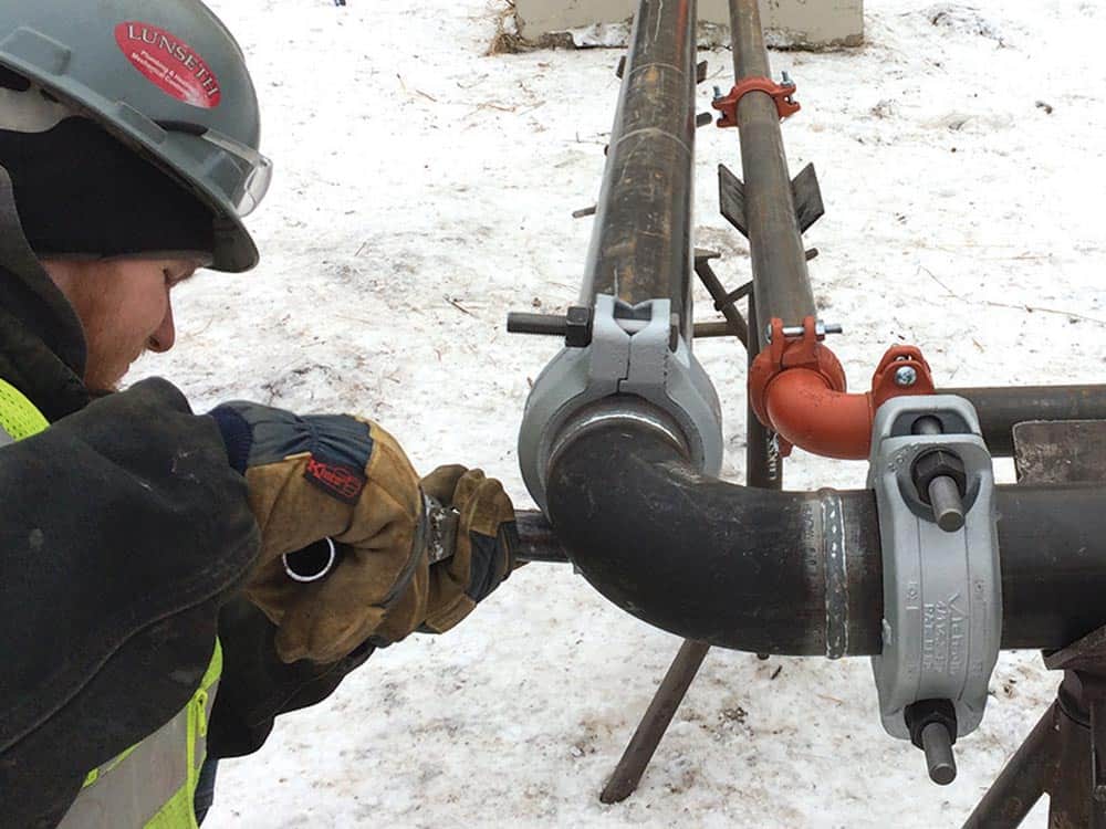 Worker repairing steam pipe with Victaulic couplings