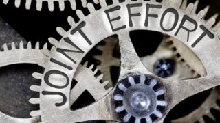 Macro photo of tooth wheel mechanism with JOINT EFFORT concept letters