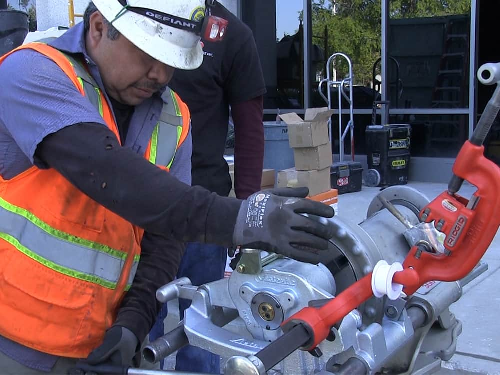 Fire protection system installer working with a Victaulic roll grooving pipe tool