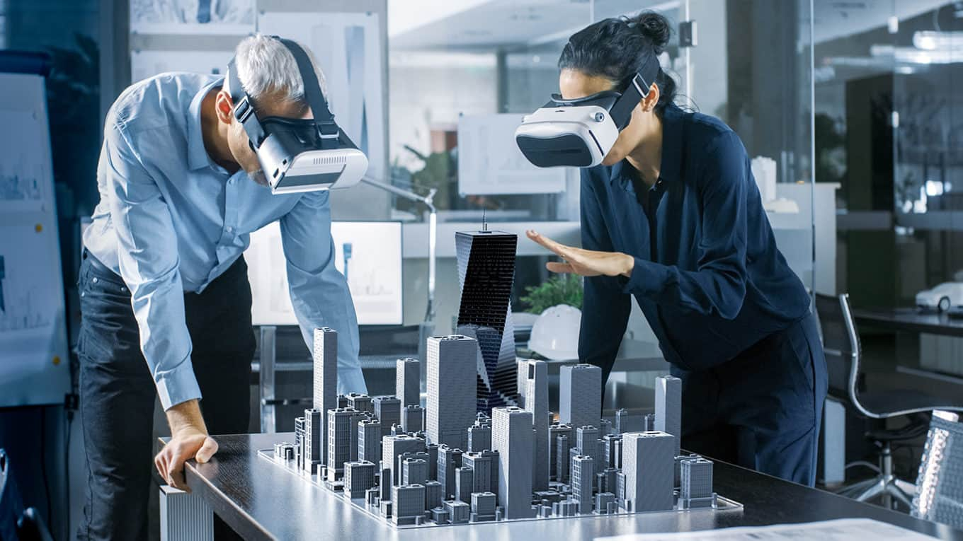 Male and Female Architects Wearing Augmented Reality Headsets Work with 3D City Model. High Tech Office Professional People Use Virtual Reality Modeling Software Application.