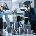 Male and Female Architects Wearing Augmented Reality Headsets Work with 3D City Model. High Tech Office Professional People Use Virtual Reality Modeling Software Application.