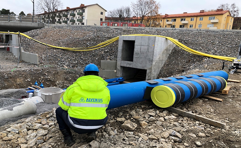 Ingénieur d'Alvenius à genoux pour examiner une section d'un tuyau dans la zone de travail