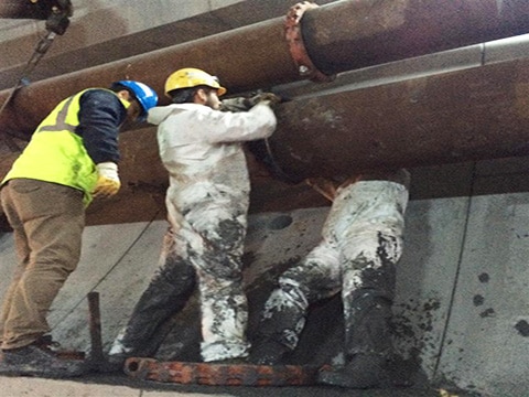 Bauarbeiter bei der Installation einer Victaulic-Kupplung Typ 77 zur Verbindung von verzinkten Stahlrohrleitungen